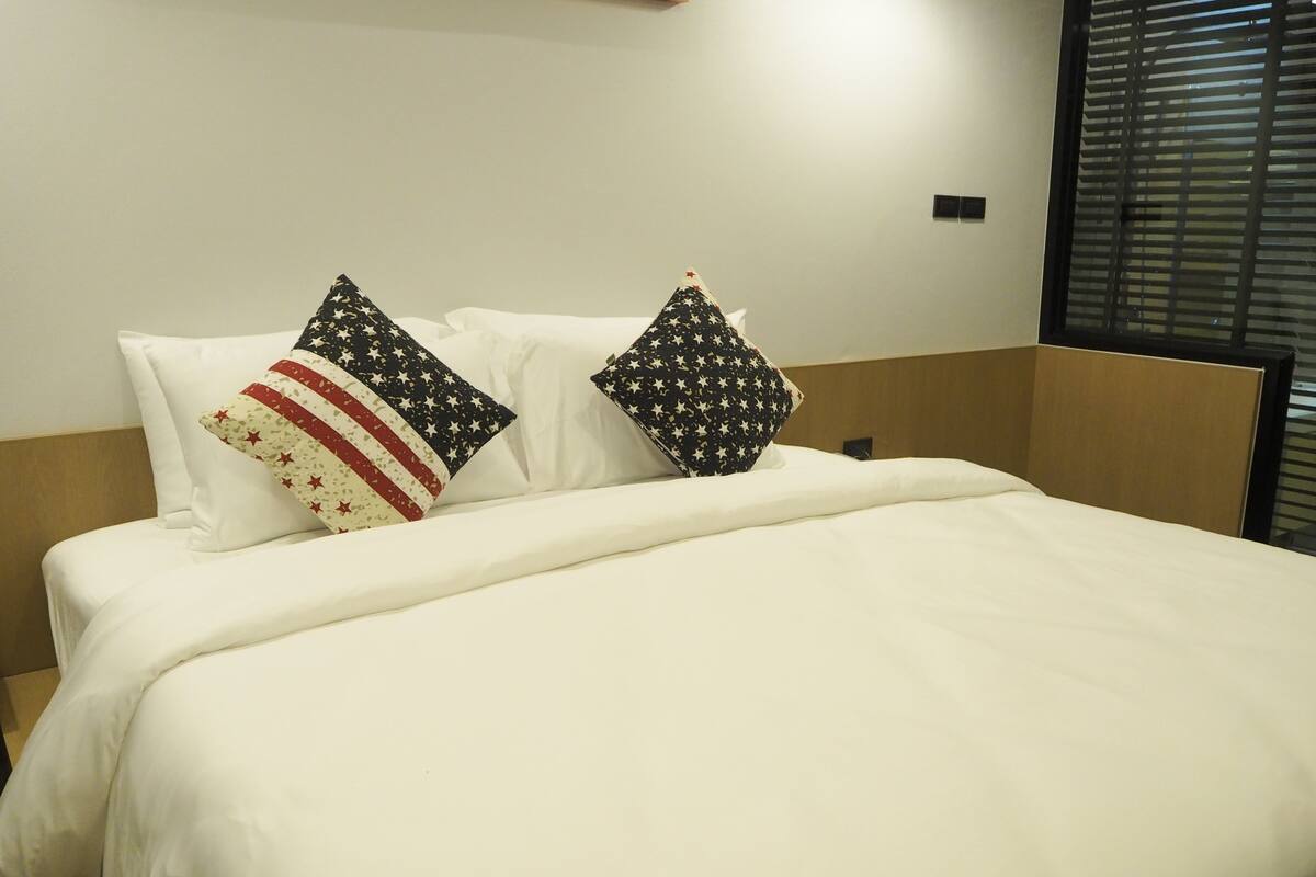 A neatly made bed with white bedding and two decorative pillows with star patterns.