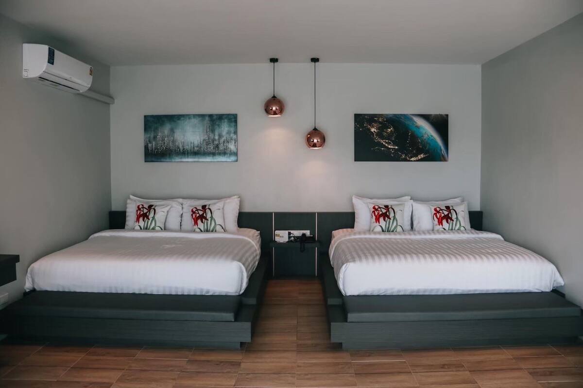 A modern hotel room with two beds, a nightstand, and artwork on the walls.