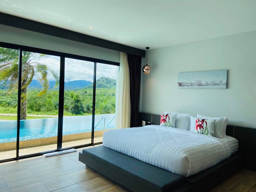 Une chambre moderne avec un grand lit, un tableau représentant un paysage urbain et une vue sur une piscine et un espace verdoyant.
