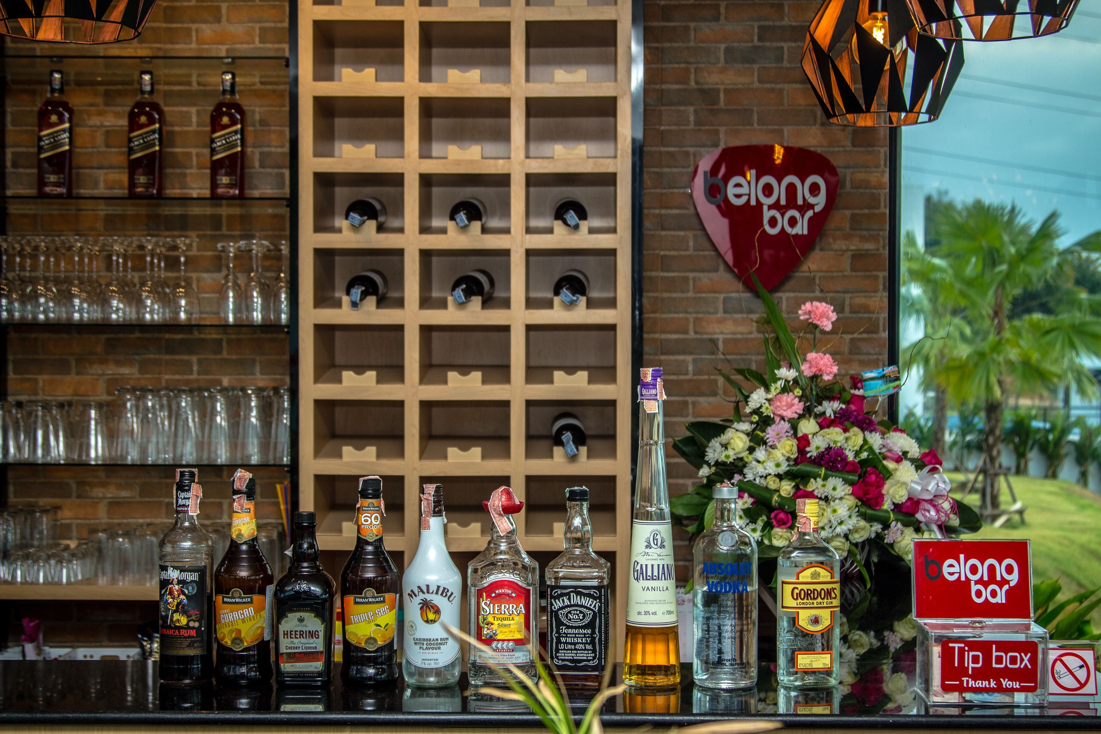 Een bar met verschillende drankflessen, glazen en een bord met de tekst 'belong bar'.