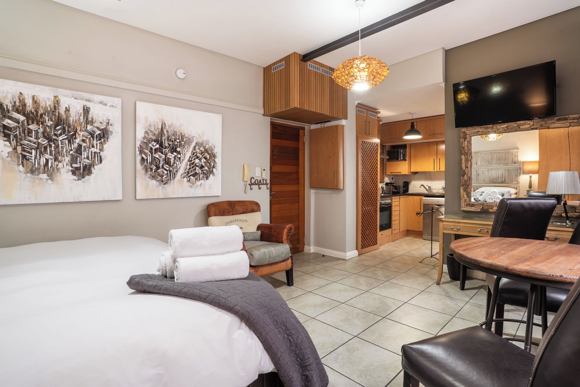Une chambre d’hôtel comprenant un lit, une chaise, une table à manger et un coin cuisine.
