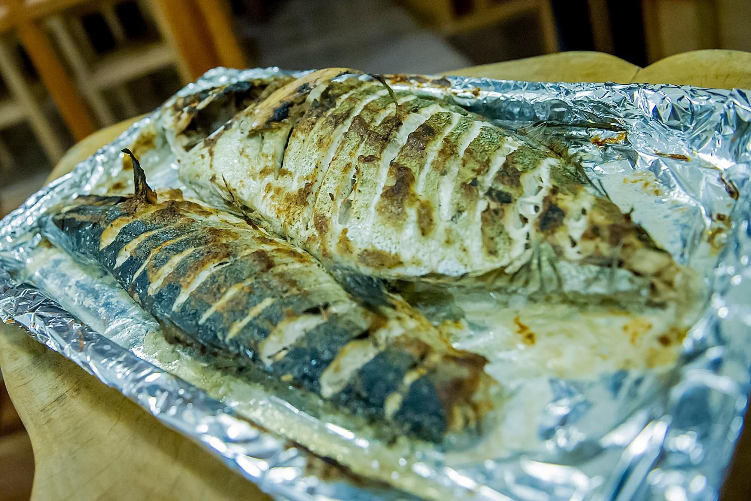 Dos peixos a la planxa sobre un safata d'alumini.