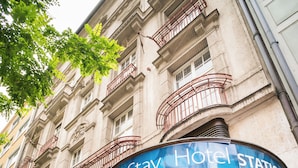 Entrada de hotel con un toldo curvo y un letrero que dice 'Stay Hotel Station'.
