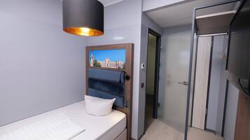 Ein modernes Schlafzimmer mit einem Bett, einer Hängeleuchte, einer Tür zu einem Badezimmer und einem an der Wand hängenden Bild.