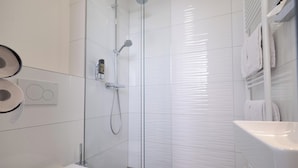 Un baño moderno con ducha acristalada, inodoro blanco y lavabo.