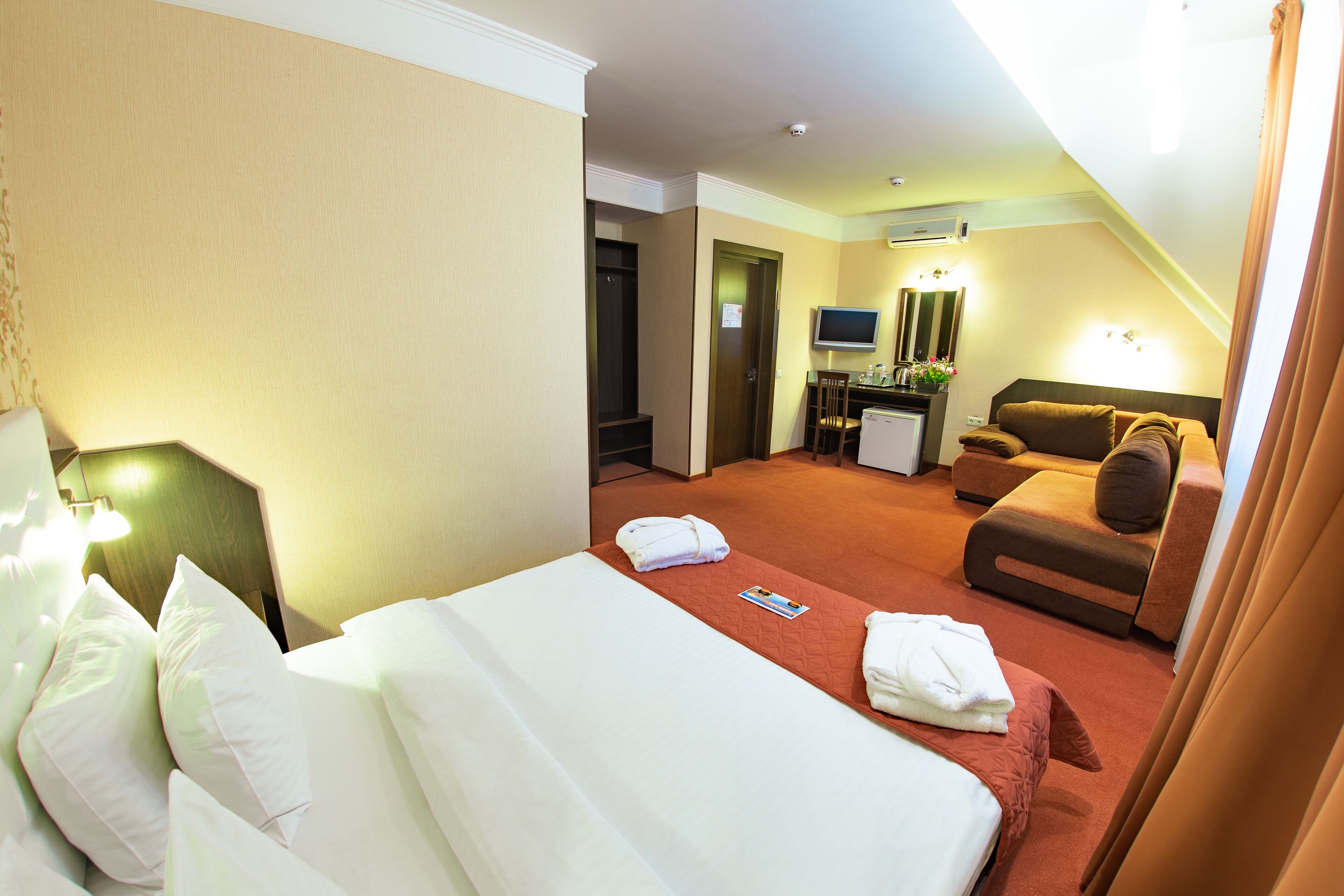 Ein Hotelzimmer mit Bett, Sofa, Schreibtisch und Fernseher.