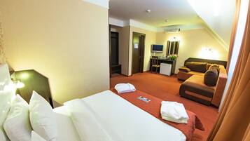 Ein Hotelzimmer mit Bett, Sofa, Schreibtisch und Fernseher.