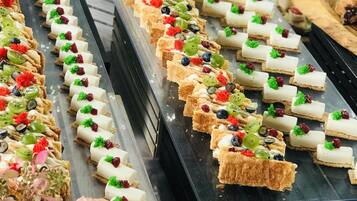 Un bufé con diversos postres y pasteles, que incluyen tartas y preparaciones con fruta, presentados en bandejas.