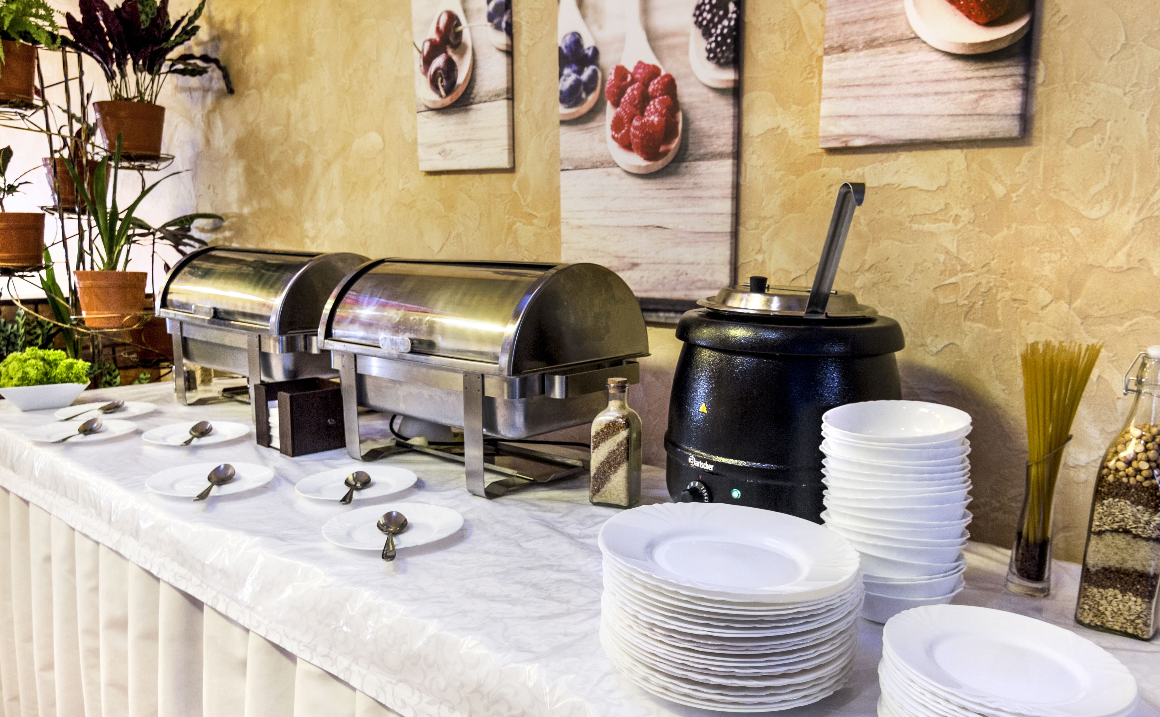 A buffet setup with a self-service food station, a coffee machine, and neatly stacked plates.