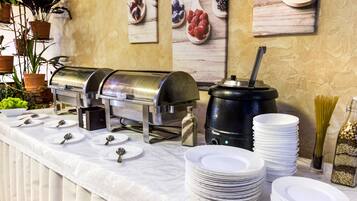 A buffet setup with a self-service food station, a coffee machine, and neatly stacked plates.