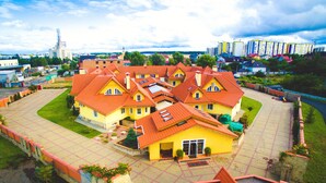 A cluster of yellow buildings with orange roofs, surrounded by a paved courtyard and a stone wall. - Kiev365 (Sofiivska Borschahivka)