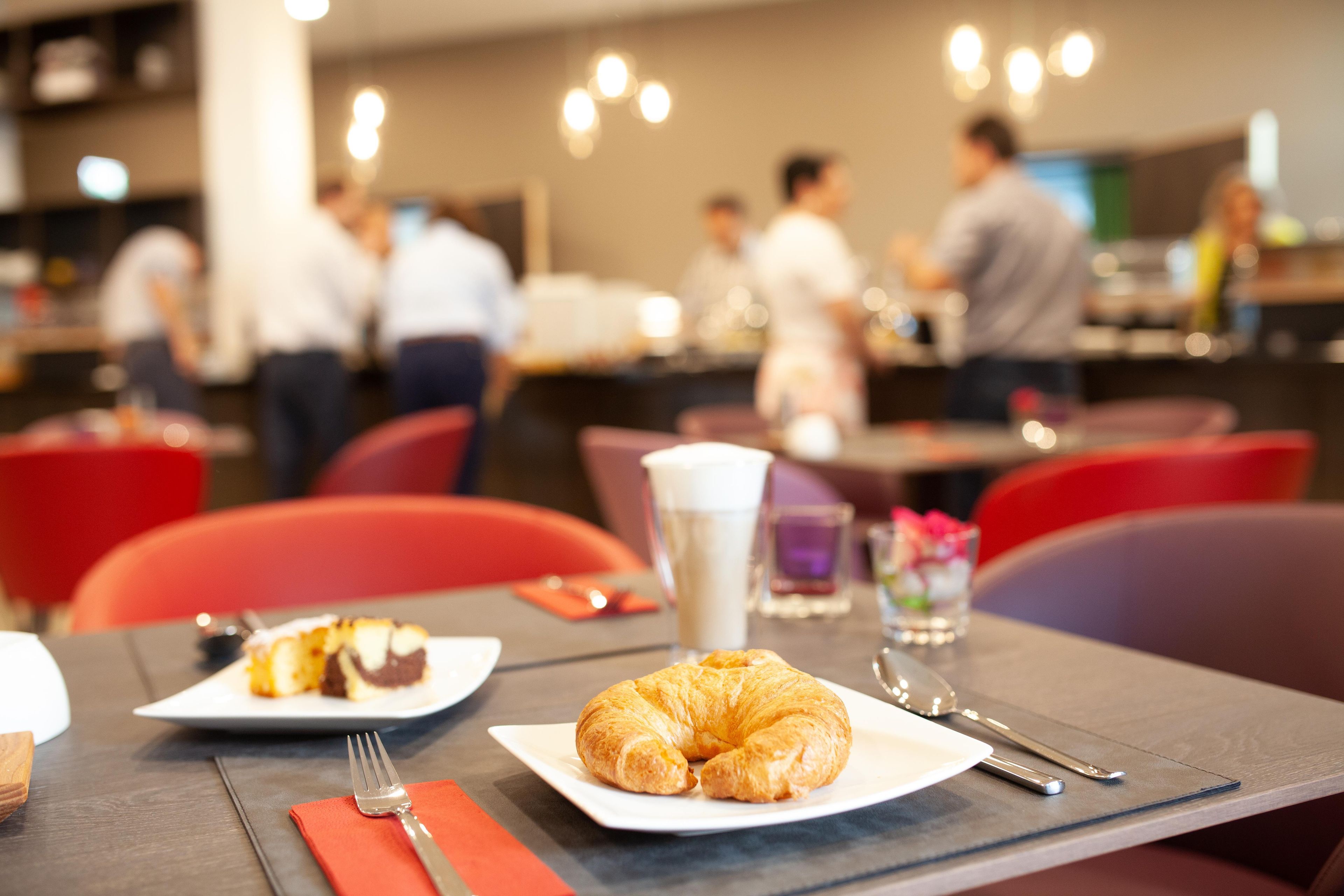 A dining area with tables, chairs, and a croissant on a plate.