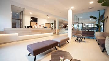 Un moderno vestíbulo de hotel con mostrador de recepción, zona de estar y un bar.