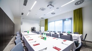 Une salle de conférence équipée de plusieurs tables, de chaises et d’un écran de projection.