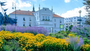 Un edificio histórico con techo de tejas rojas, paredes blancas y un balcón con jardineras florales.