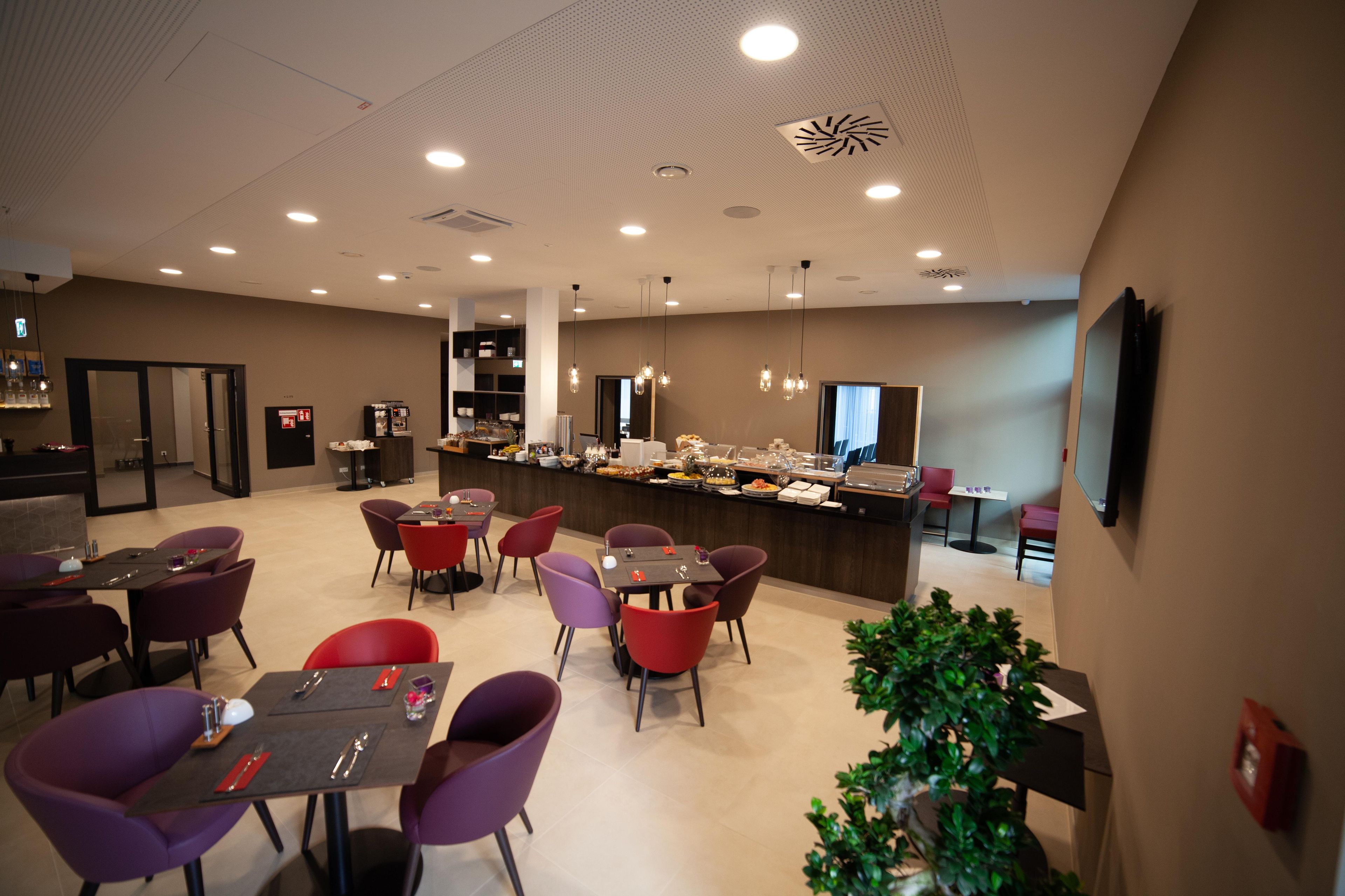 A modern restaurant with a bar area, multiple dining tables, and chairs.