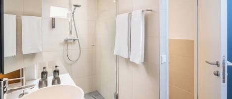 Un baño moderno con un lavamanos grande, una ducha y un box de ducha con paredes de vidrio.