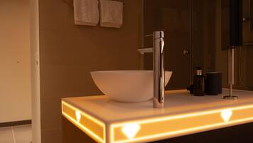 Un baño moderno con un lavabo blanco, un espejo y un perchero para toallas.