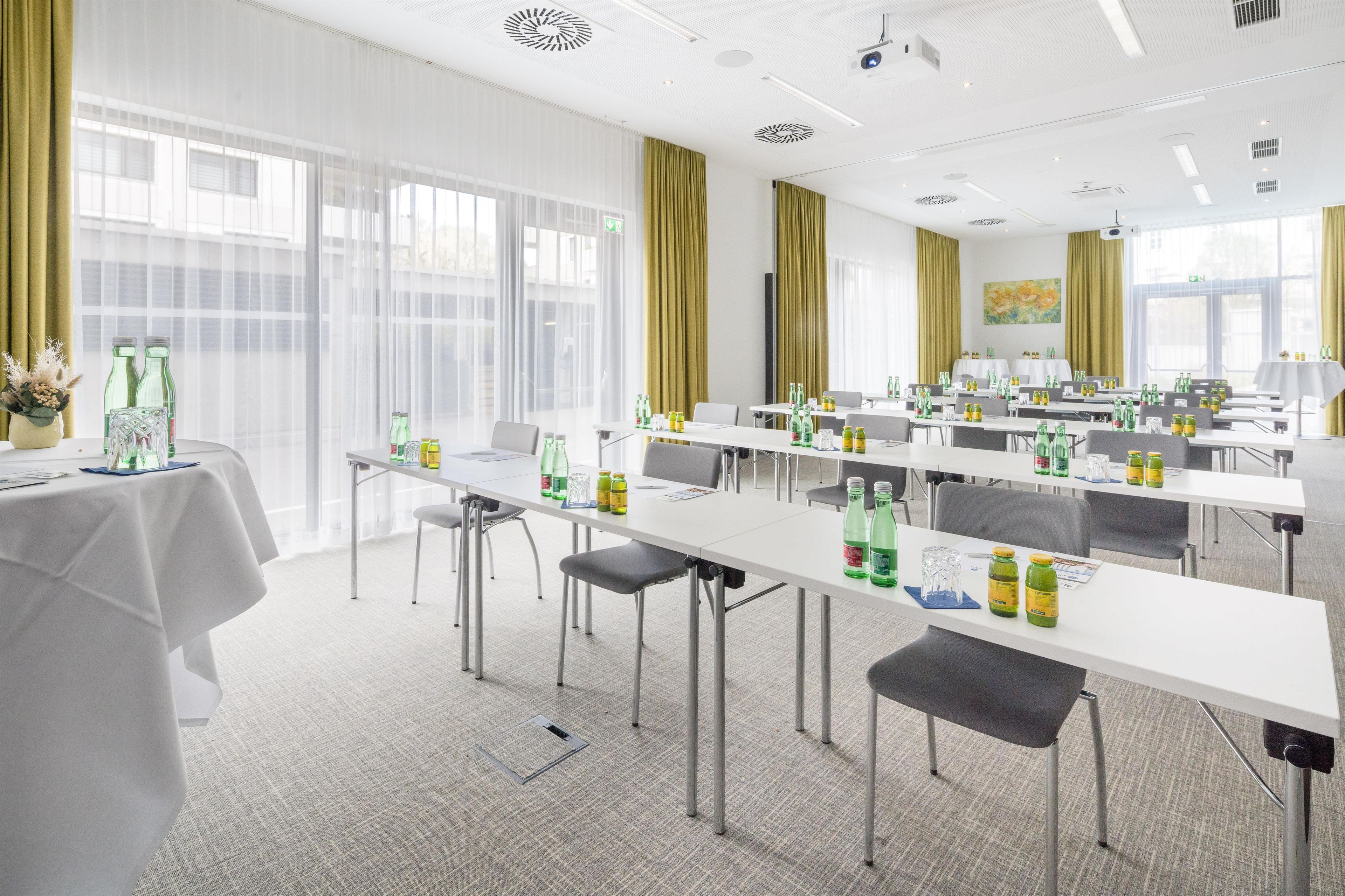 A conference room with tables, chairs, and bottles of water.