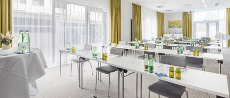 A conference room with tables, chairs, and bottles of water.
