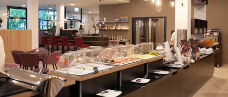 A buffet area with various food options, seating arrangements, and a bar in the background.