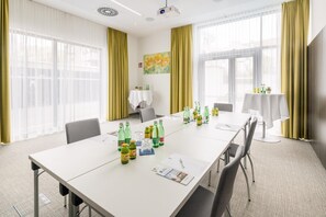 Une salle de conférence avec une longue table, des chaises et divers objets disposés sur la table, notamment des bouteilles et des papiers.