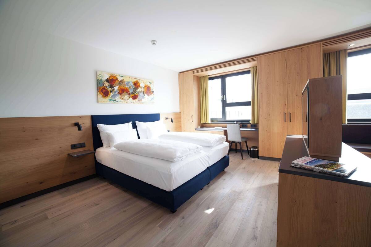 Una habitación de hotel moderna con una cama grande, un escritorio y un armario.