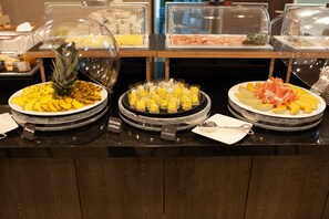 A buffet with various food items including pineapple slices, scrambled eggs, and avocado slices.