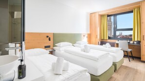 A hotel room with two beds, a desk, a chair, a window with curtains, and a view of a building. - Best Western Hotel Tulln (Tulln an der Donau)