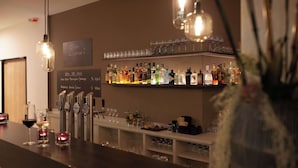 Zona de bar con estantes llenos de botellas de licor, vasos y un menú en la pizarra.