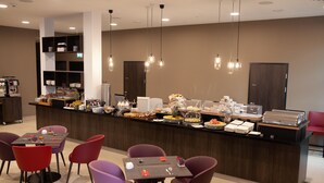 Un bar à petit-déjeuner moderne proposant une variété de plats, entouré de sièges avec des chaises rouges et violettes.
