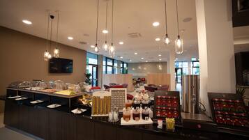 A buffet area with various food options, a coffee station, and a seating area with tables and chairs.