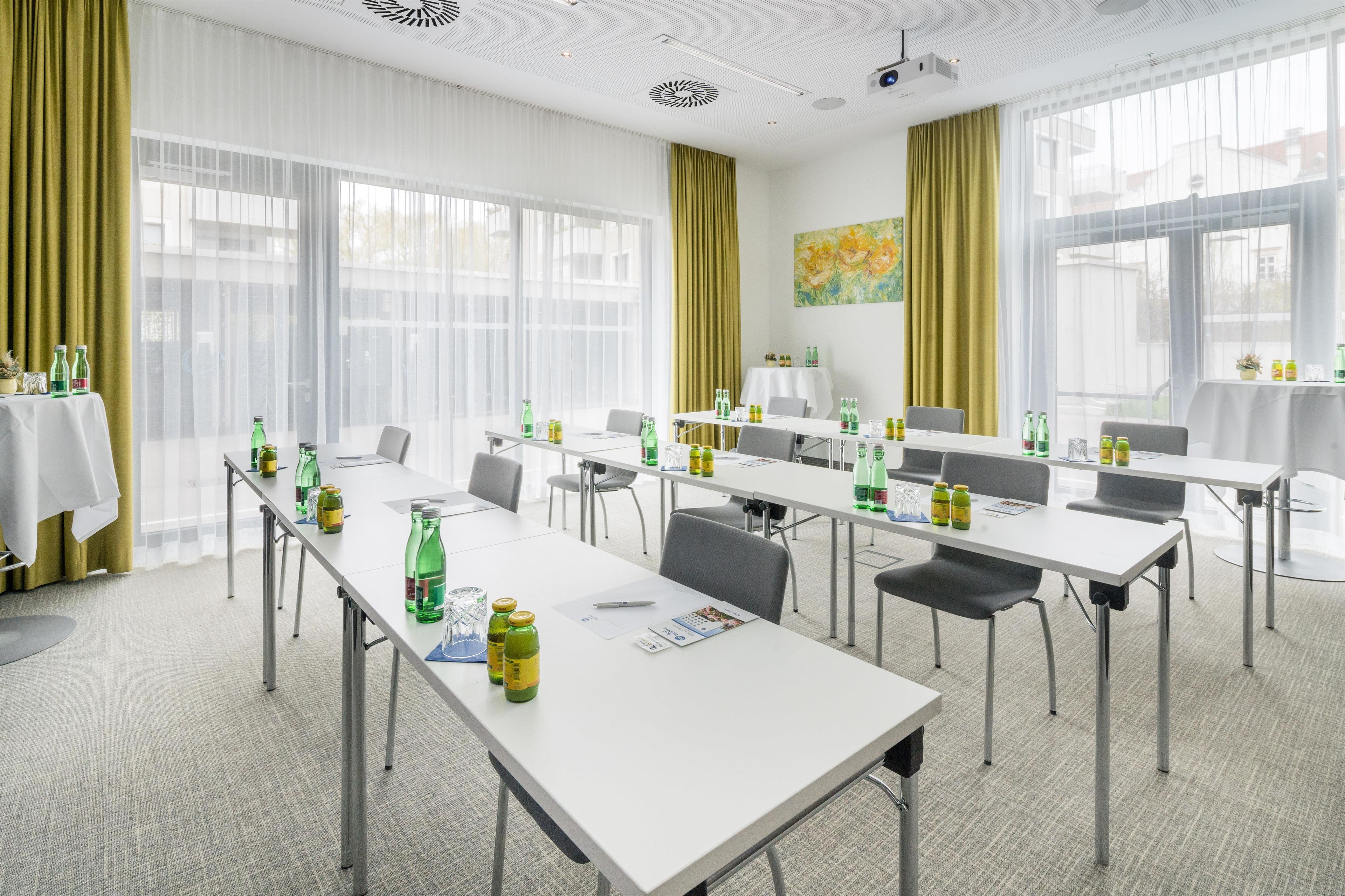 Un salón de conferencias con mesas, sillas y diversas bebidas.