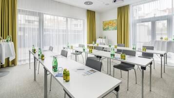 Un salón de conferencias con mesas, sillas y diversas bebidas.