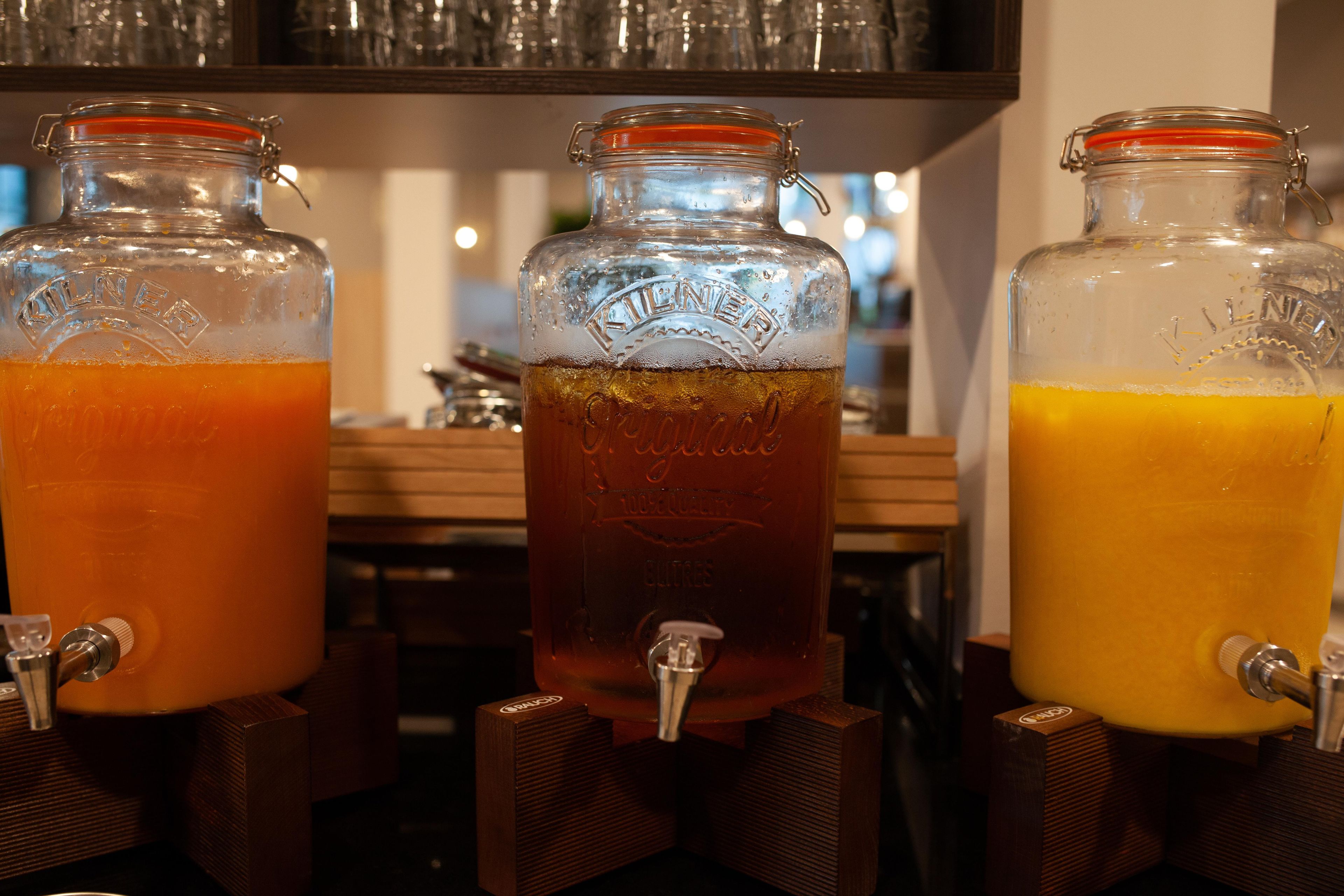 Three glass dispensers with taps, each containing a different colored beverage.