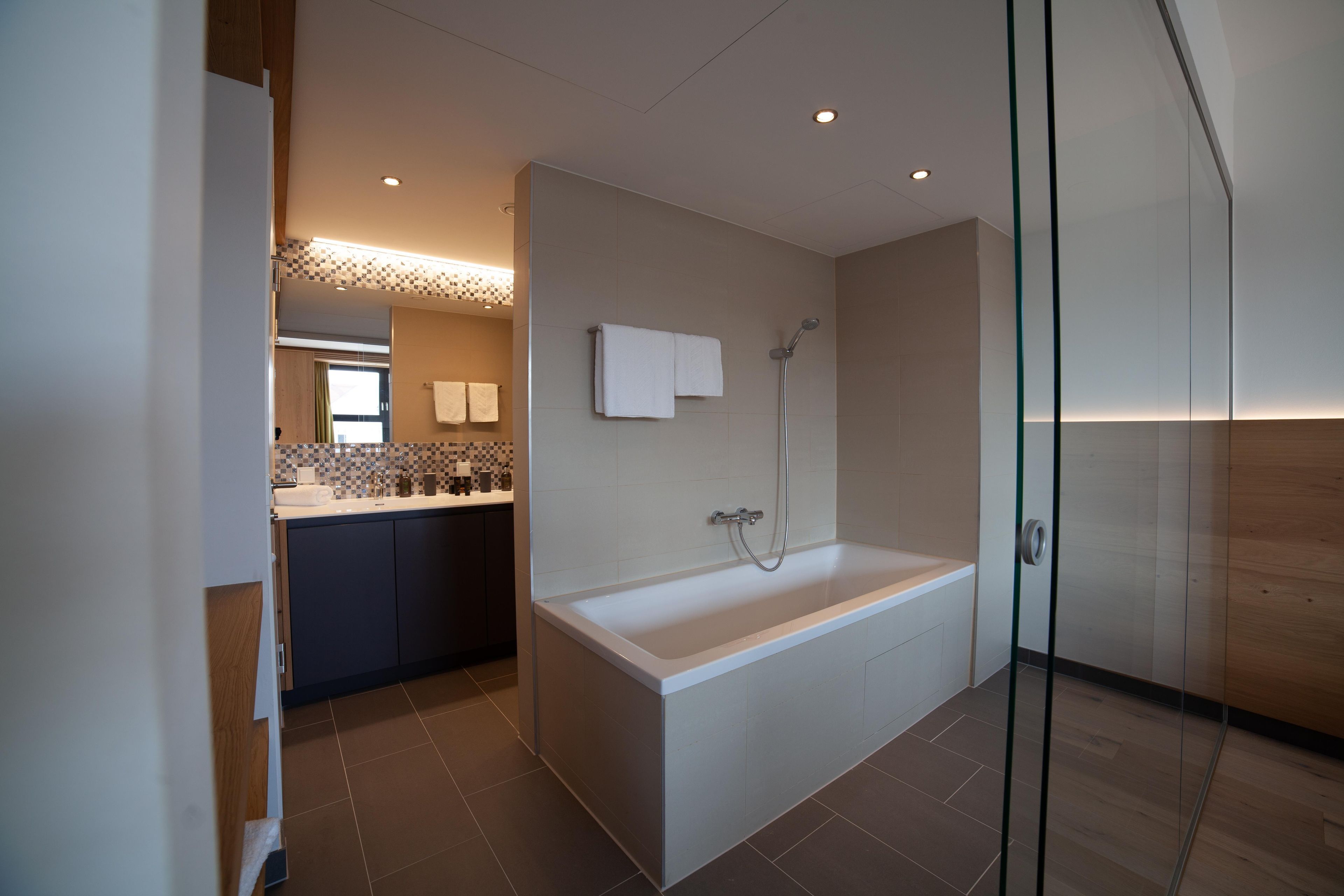 A modern bathroom with a bathtub, shower, and a glass-enclosed shower area.