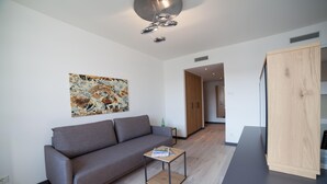 A modern living room with a grey sofa, a coffee table, and a wooden cabinet. - Best Western Hotel Tulln (Tulln an der Donau)