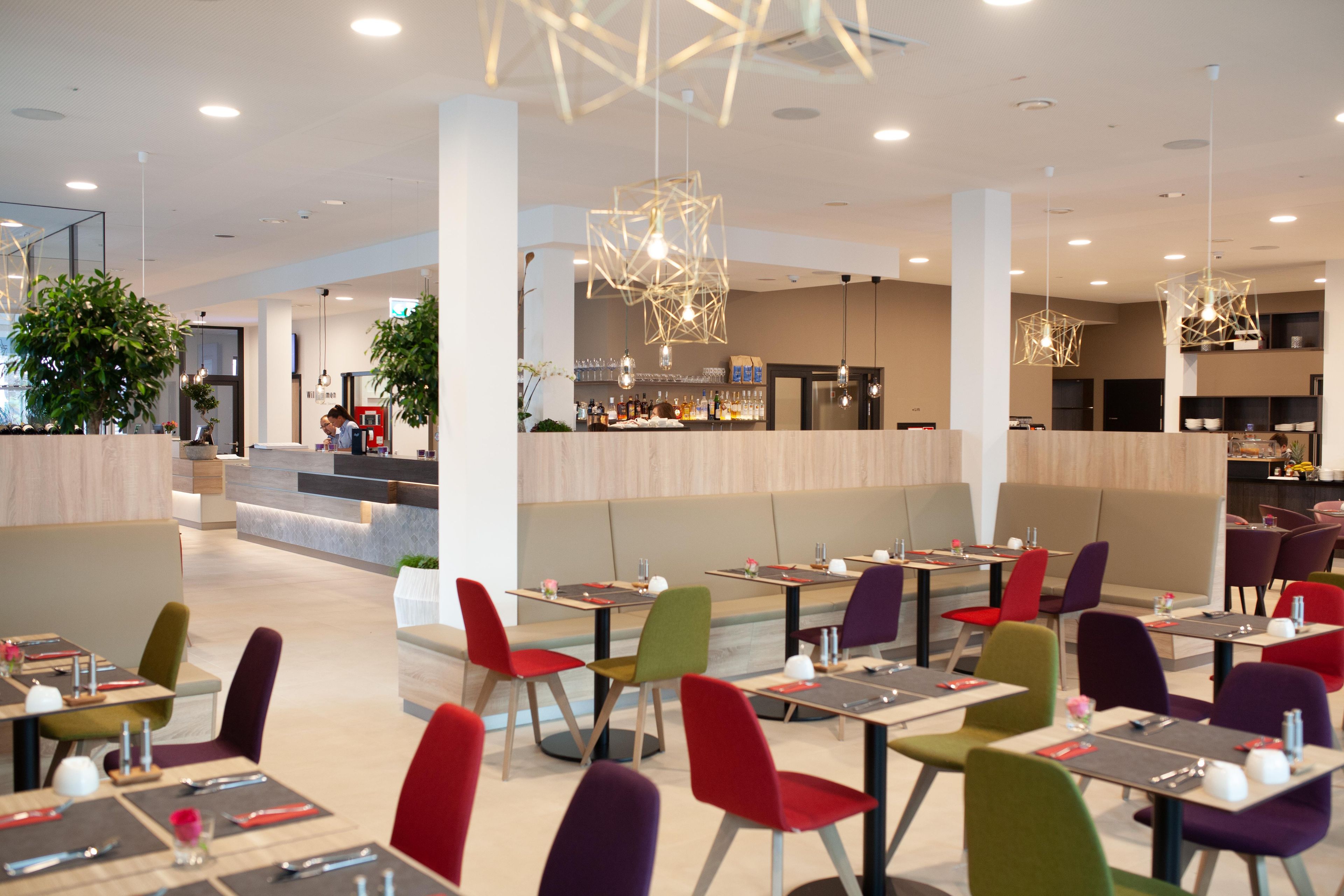 A modern restaurant with multiple dining areas, including a bar and a seating area with tables and chairs.