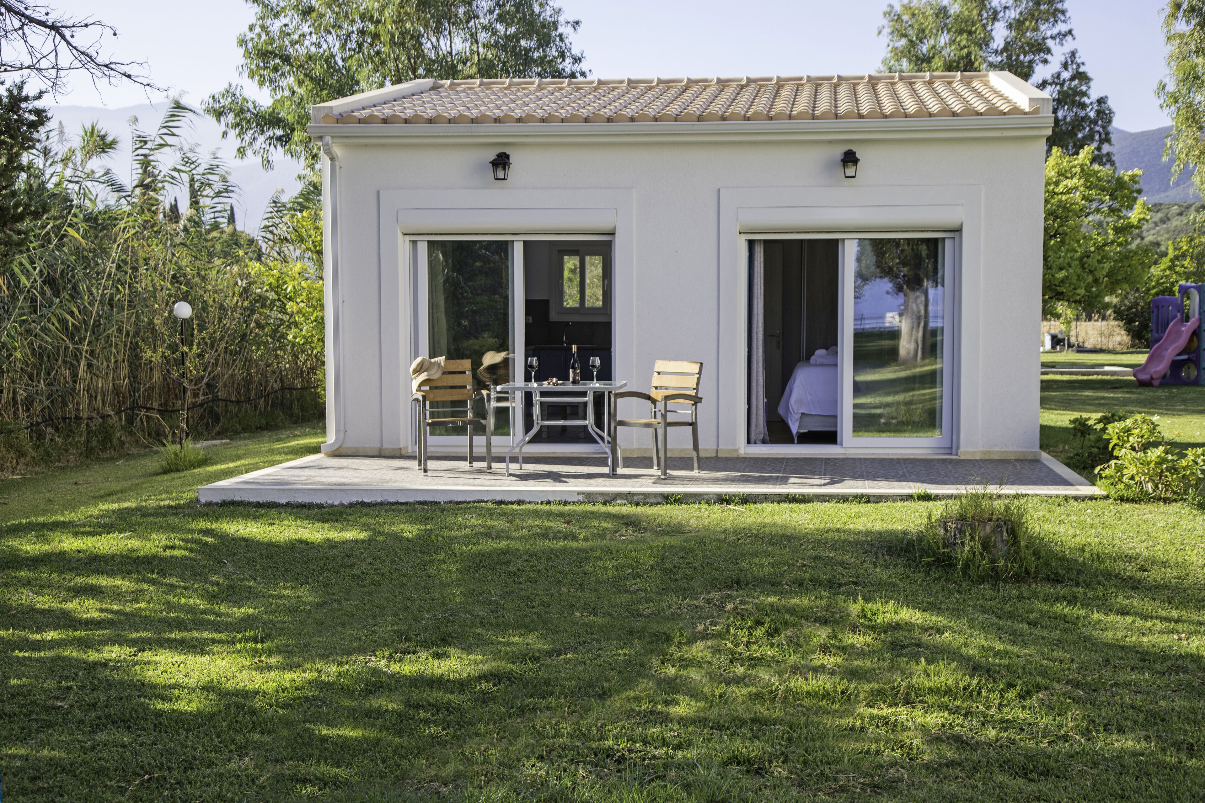 Une maison moderne dotée d’un patio, de portes-fenêtres coulissantes et d’un coin repas avec du mobilier d’extérieur.