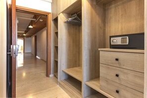 A hallway with wooden flooring, a wardrobe with a combination lock, and a door leading to another room.
