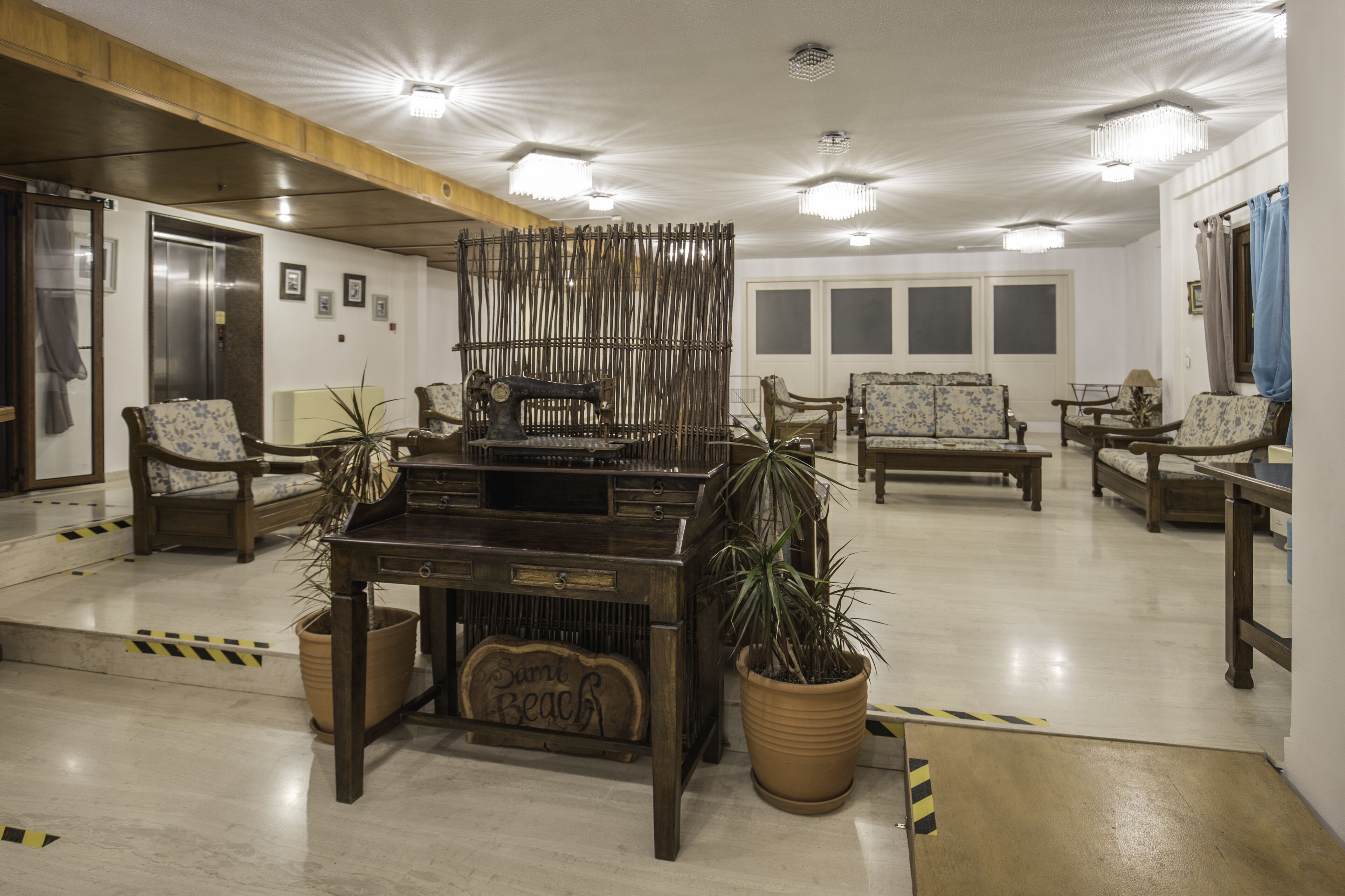 A lobby with wooden furniture, potted plants, and a vintage sewing machine.