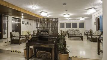 A lobby with wooden furniture, potted plants, and a vintage sewing machine.