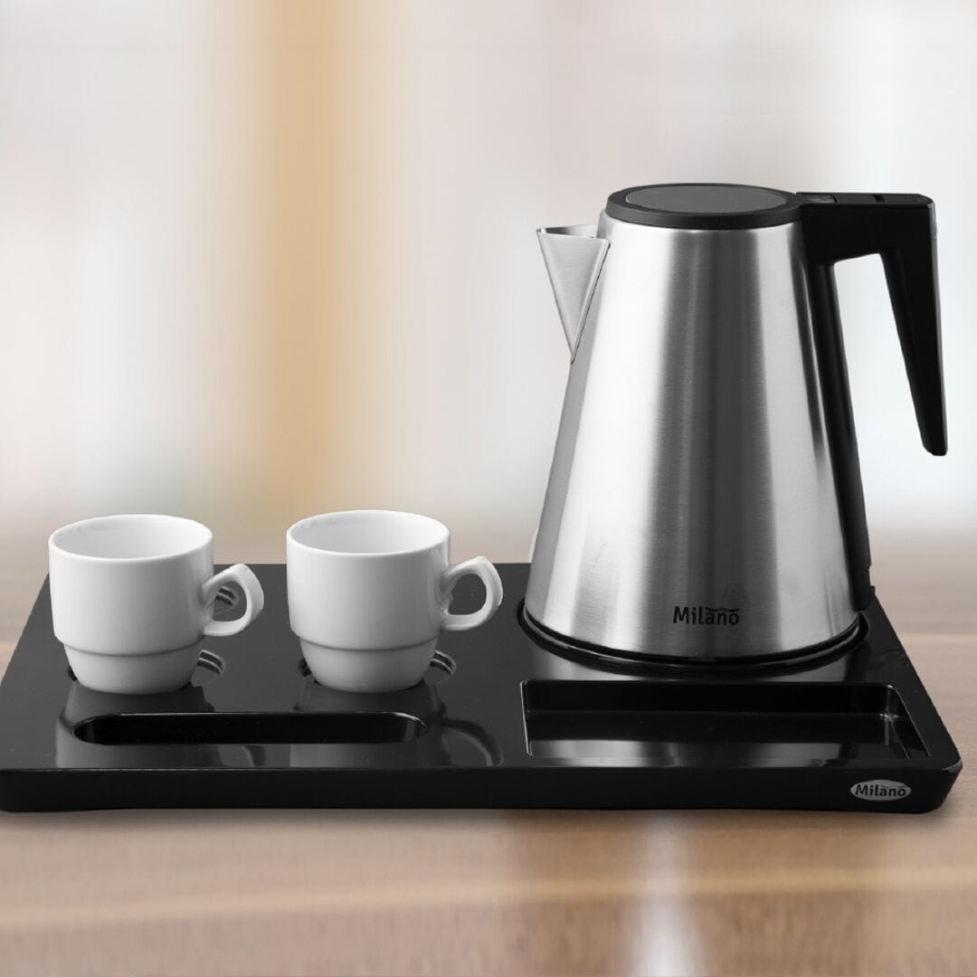 A black tray with a stainless steel coffee maker and two white cups on a wooden surface.