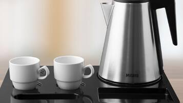 A black tray with a stainless steel coffee maker and two white cups on a wooden surface.