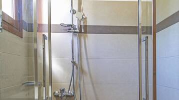 A bathroom with a glass-enclosed shower, a white sink, and tiled walls.