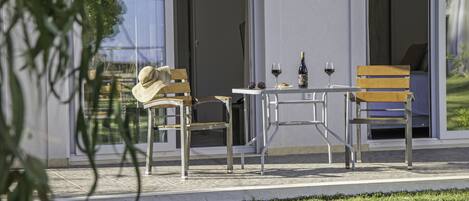 Een modern buiten eetgedeelte met een tafel en stoelen, een fles wijn en een glas wijn op de tafel.
