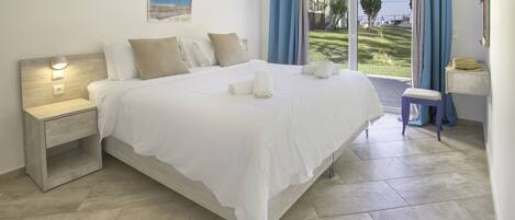 Un dormitorio con cama, mesita de noche, ventana con cortinas y vista al exterior.