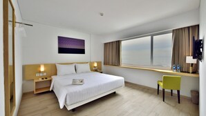 A modern hotel room with a large bed, bedside tables with lamps, a desk with a chair, a window with curtains, and a city view. - Whiz Prime Hotel Sudirman Pekanbaru (Pekanbaru)