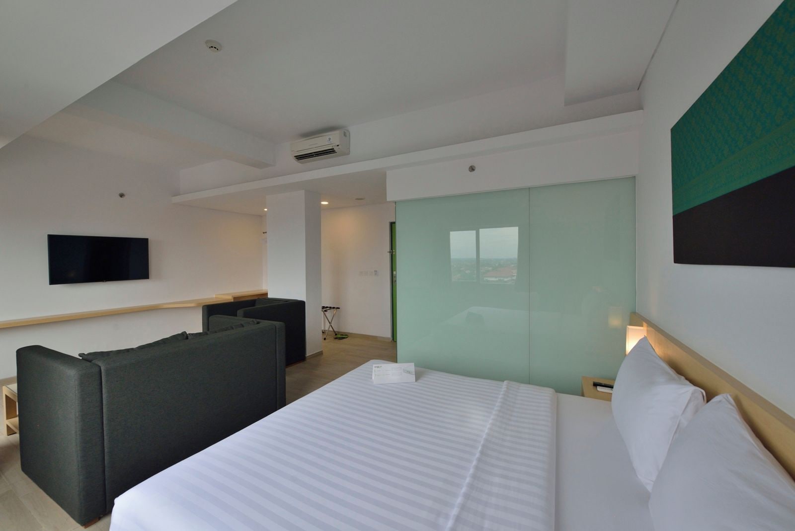 Une chambre d’hôtel comprenant un lit, un coin salon, une télévision et une vue par la fenêtre.