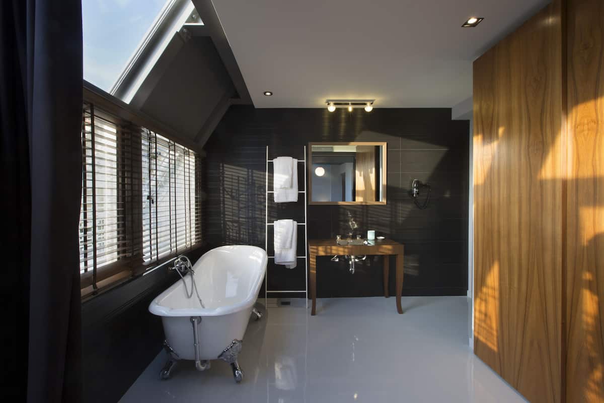 A modern bathroom with a freestanding bathtub, a vanity with a mirror, and a skylight above.